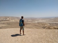 a man standing on top of a hill overlooking a desert